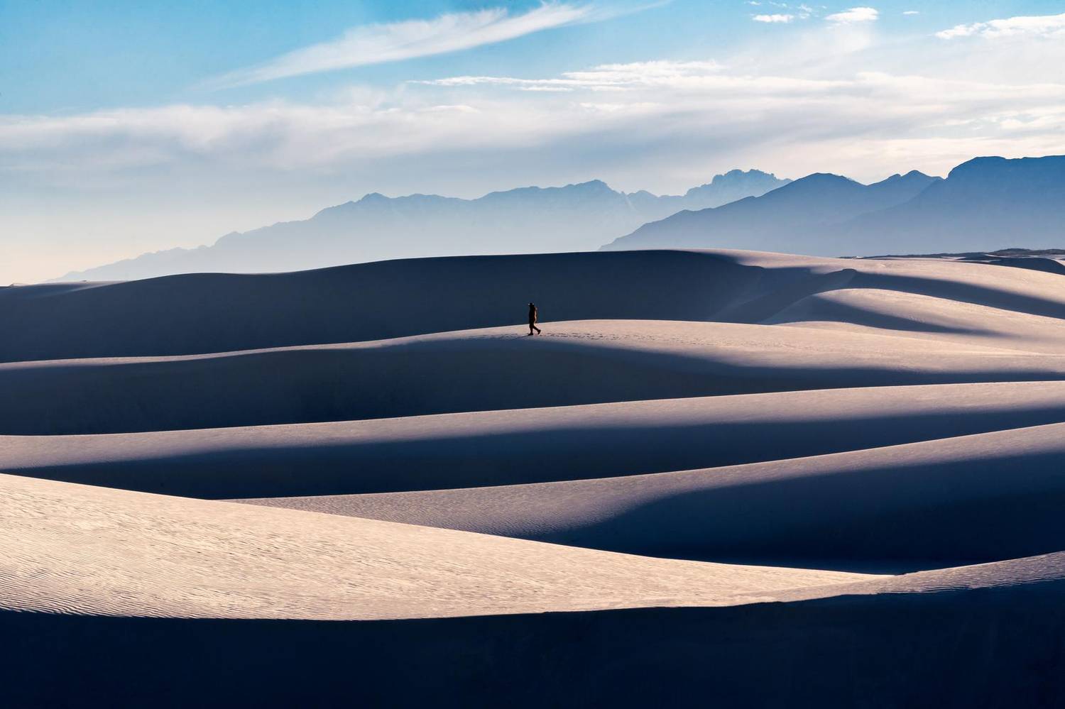Sunlit desert sand dunes with mountains in the distance