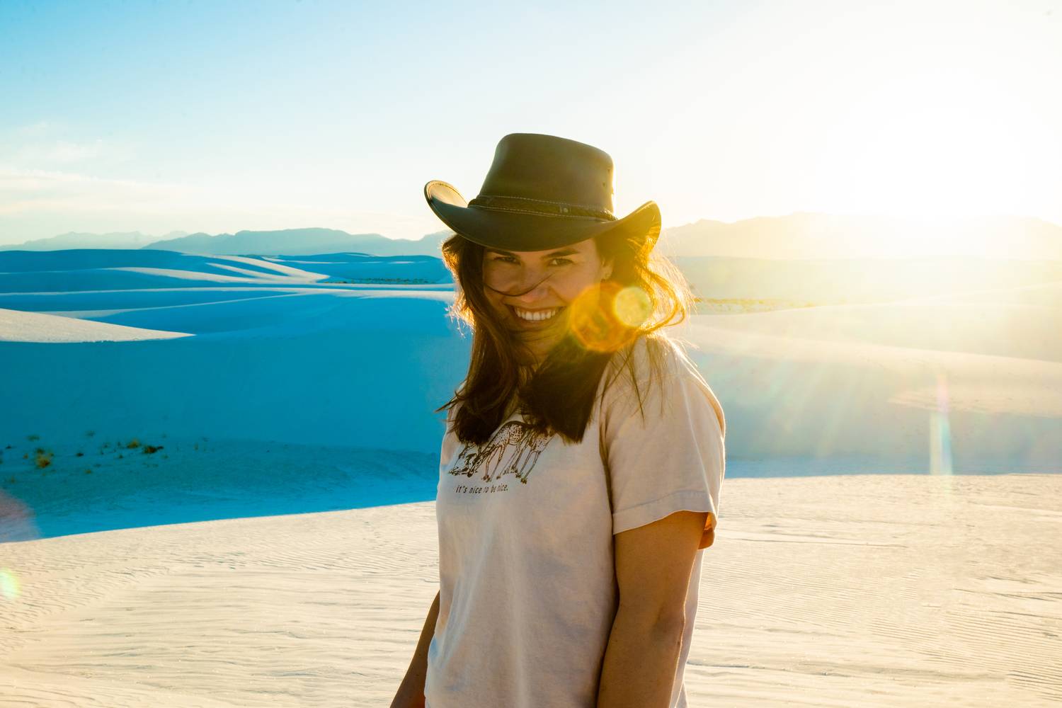 Woman in a cowboy hat backlit by sunset at White Sands