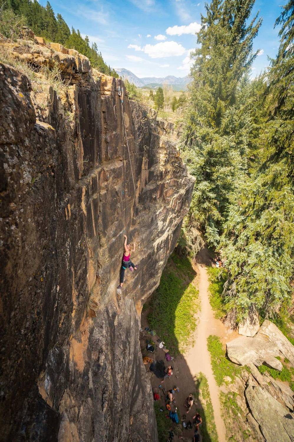 Aerial view of a rock climber ascending a cliff face above a canyon