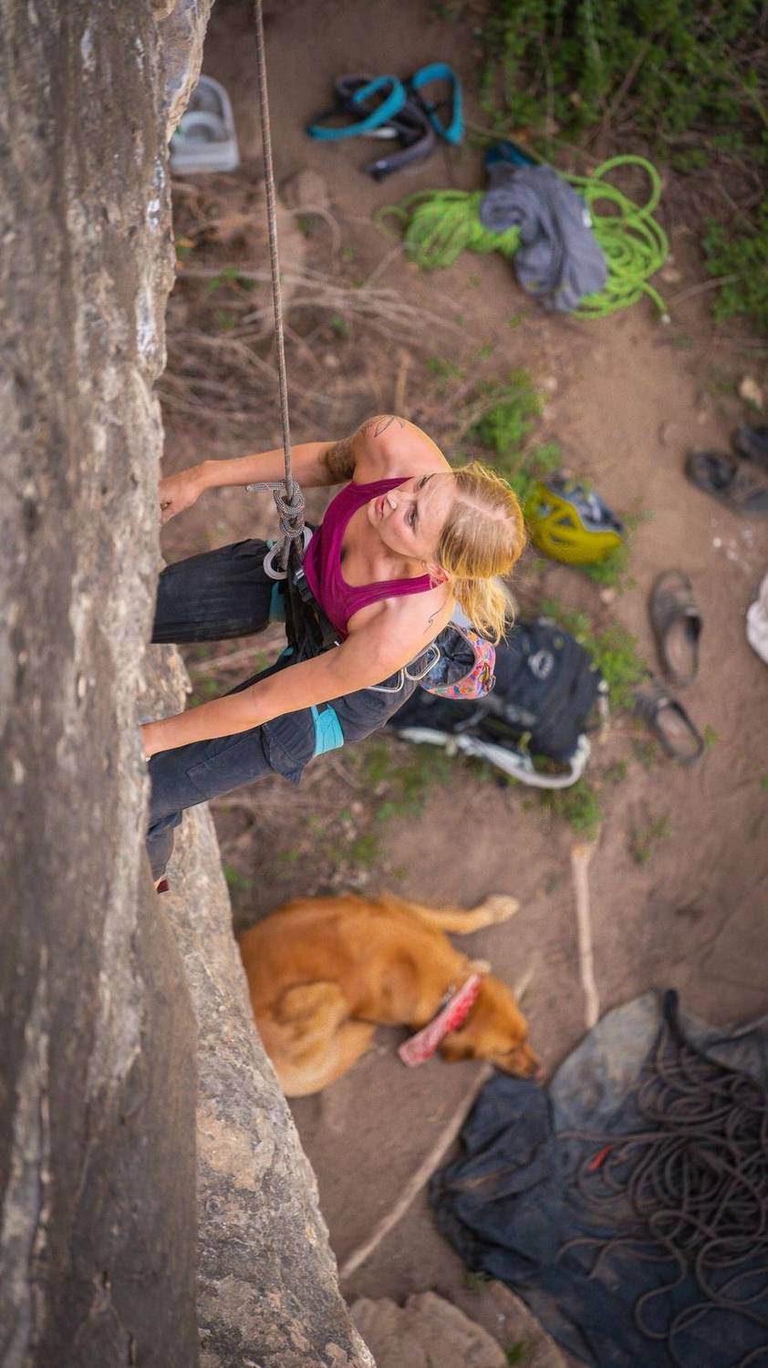 Overhead view of a climber on a rock face with a dog resting below