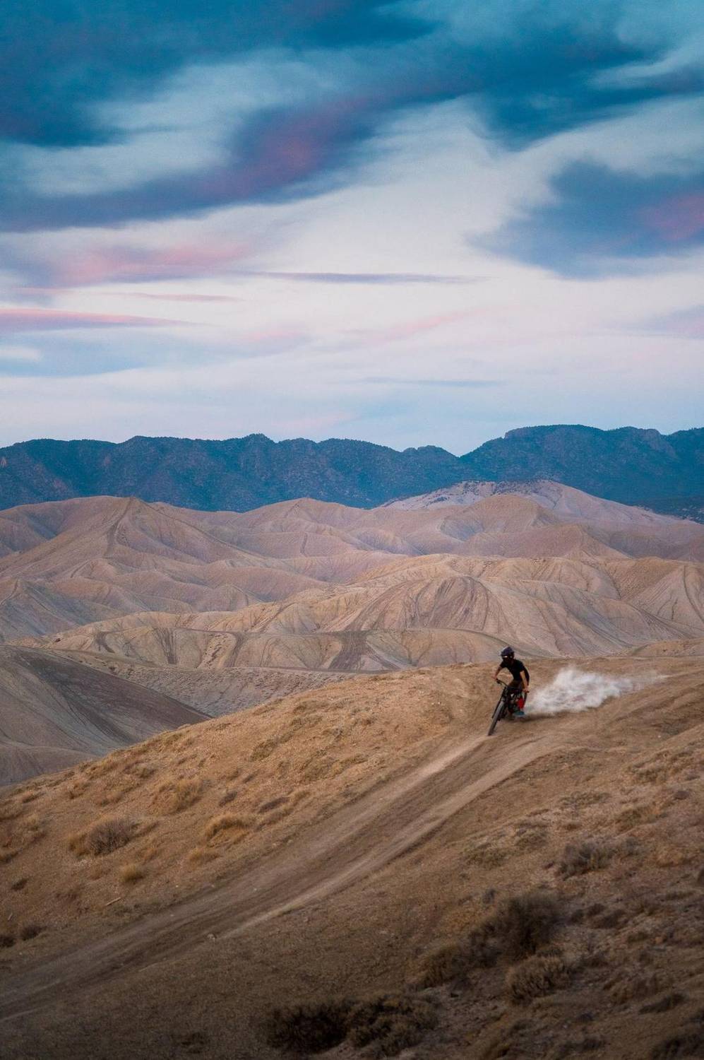 Mountain biker riding a desert ridge trail at dusk