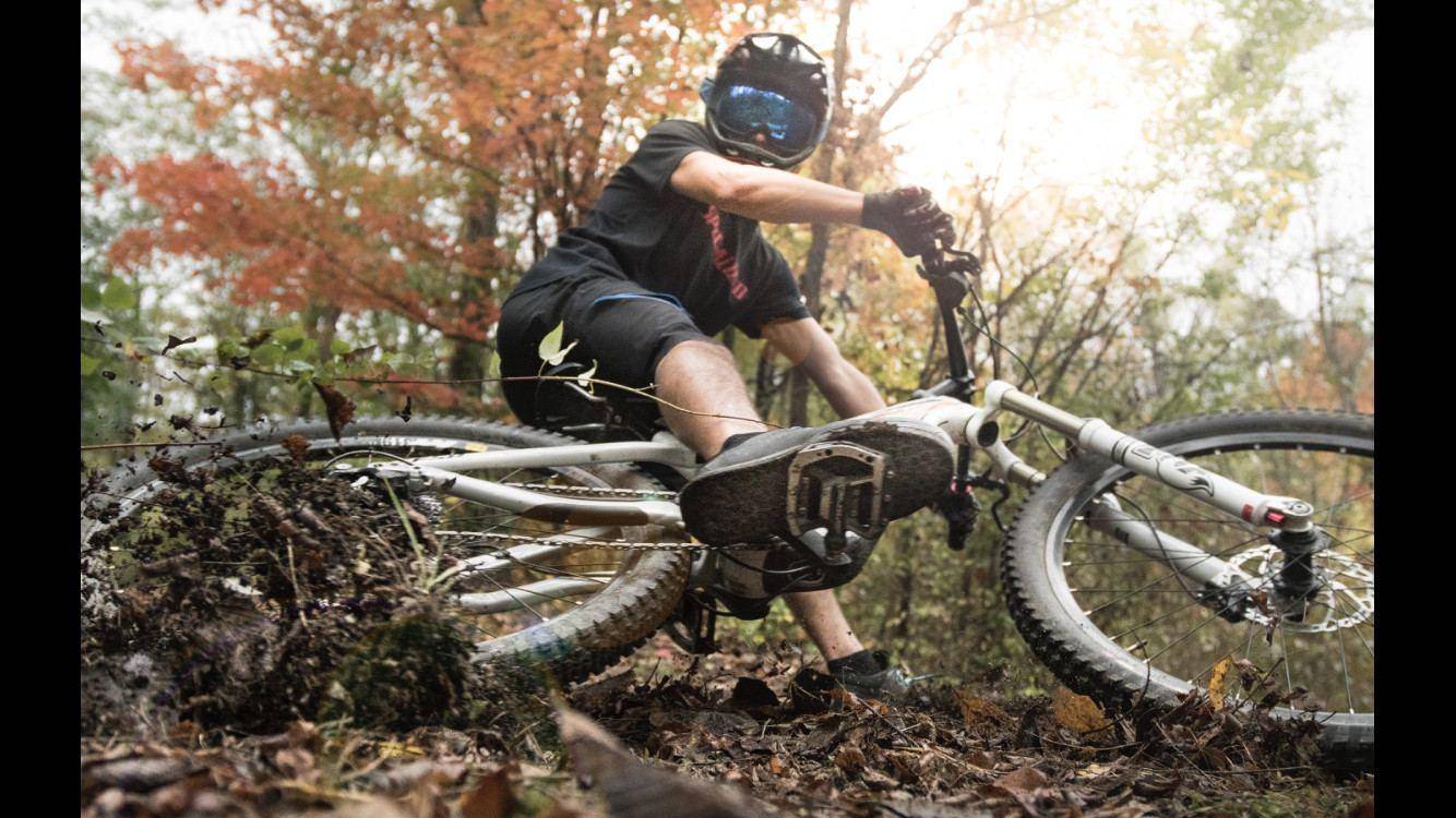 Close-up of a mountain biker riding through fallen autumn leaves