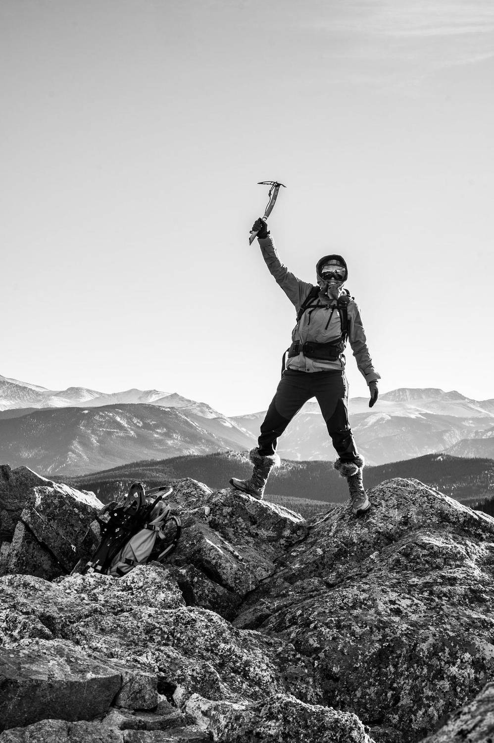 Black and white photo of a hiker celebrating on a mountain summit