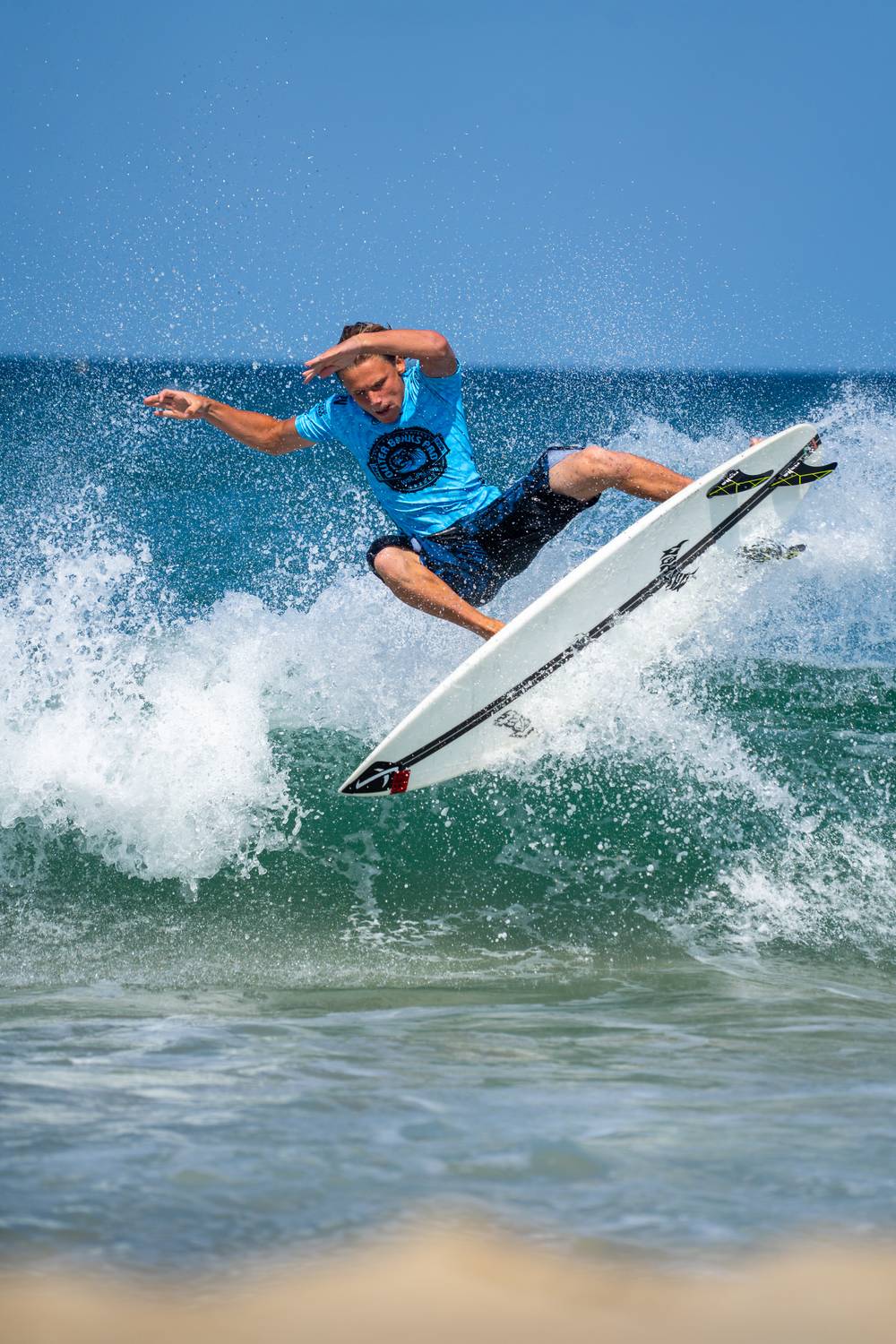Surfer launching an air maneuver above a breaking wave