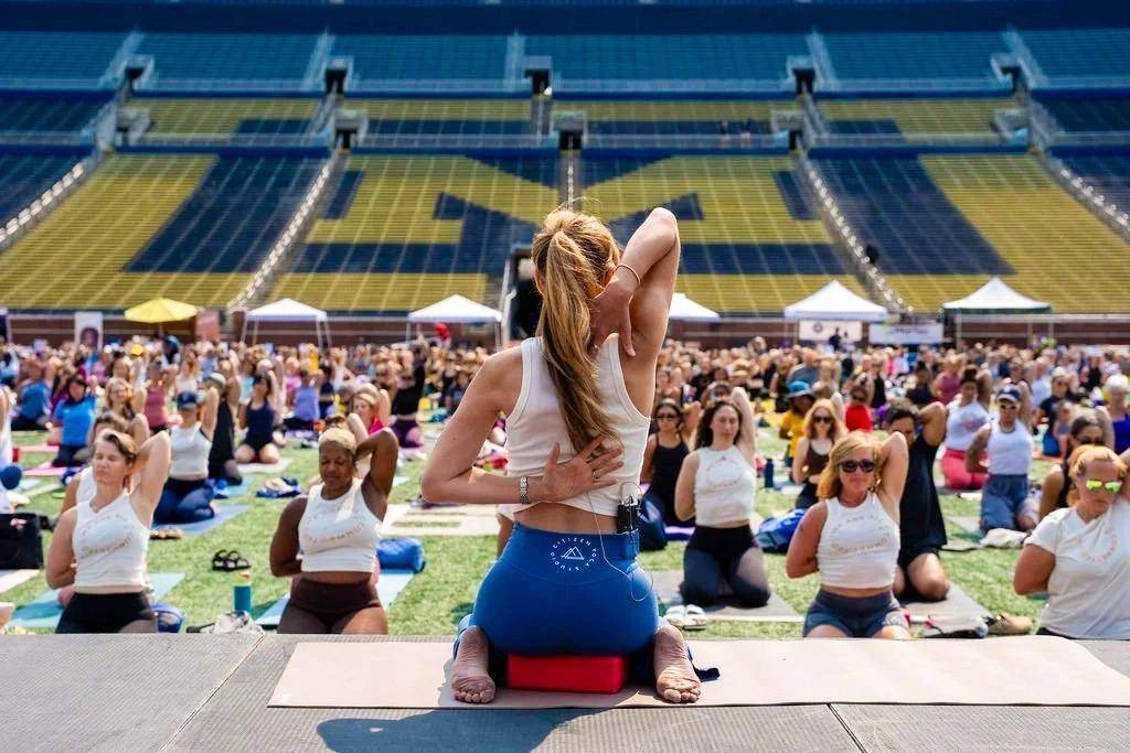 Yoga class stretching together in a sunlit stadium