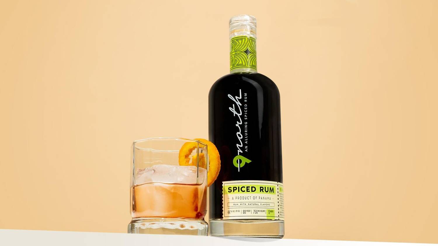 Spiced rum bottle beside a cocktail on a warm background