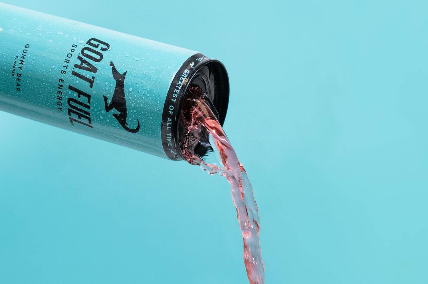 Sports energy drink can pouring against a teal background