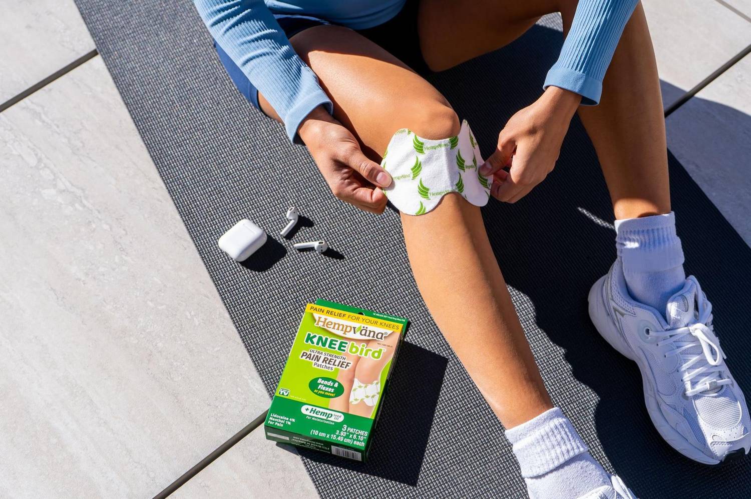 Person applying a pain relief patch to their knee