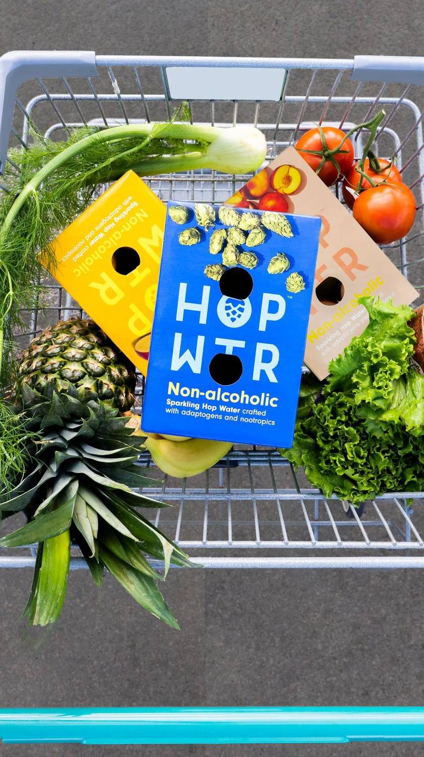 Sparkling hop water boxes in a grocery cart with fresh produce