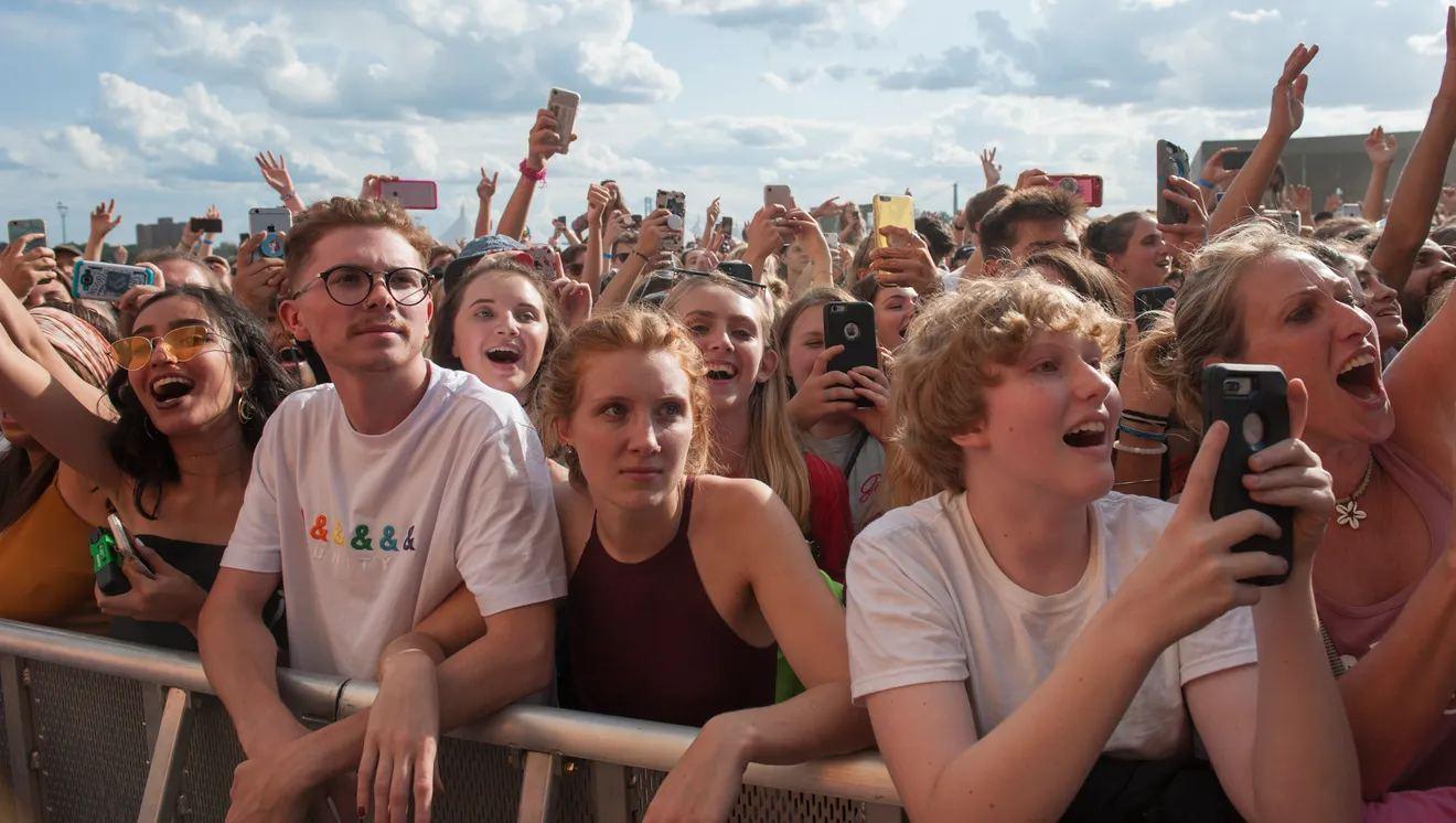 Crowd cheering and holding up phones at an outdoor concert