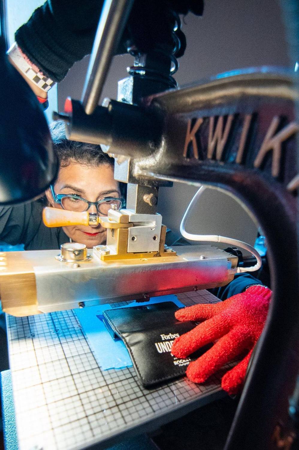 Close-up of a craftsperson using a precision tool on a leather wallet