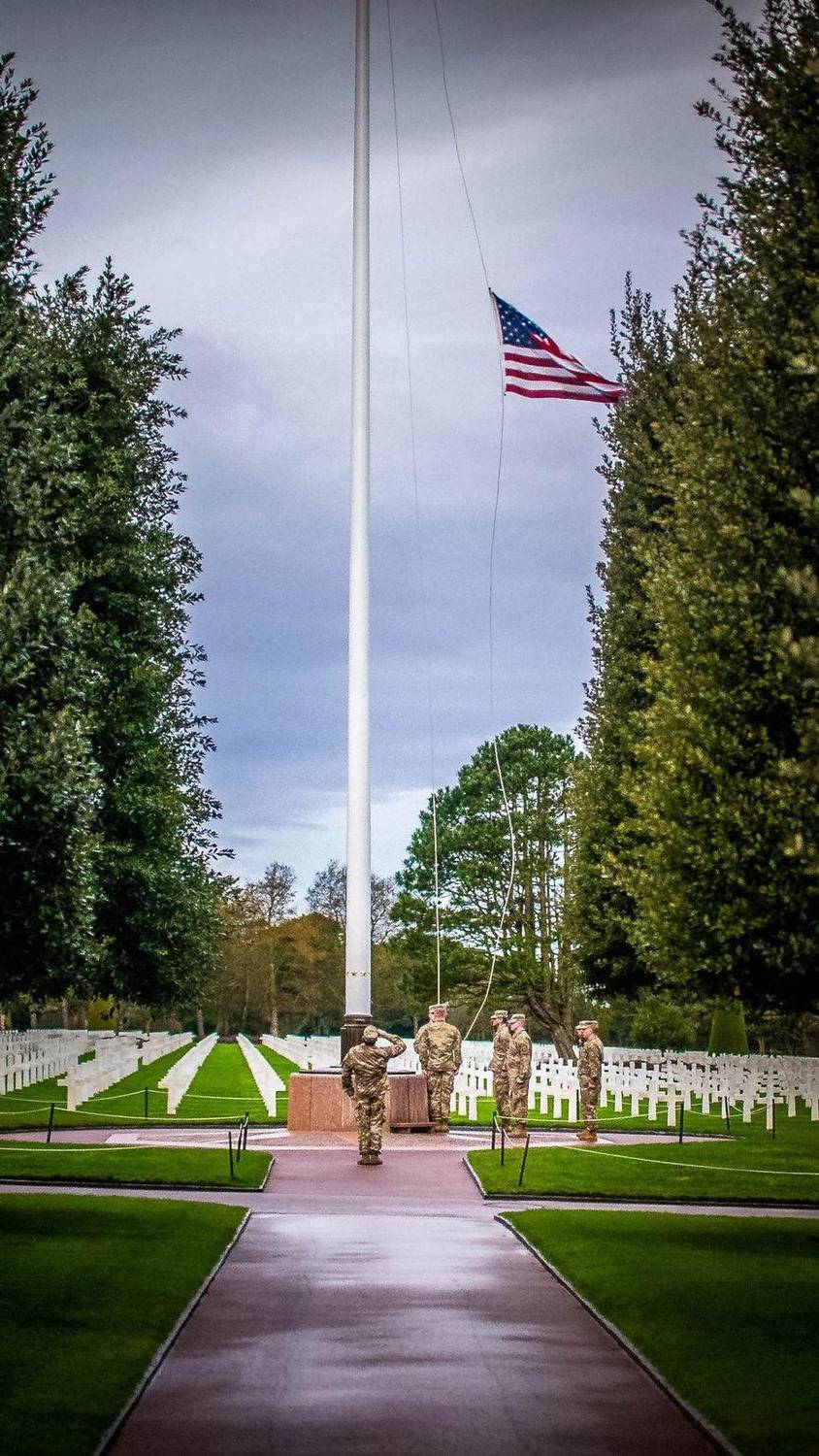 Soldiers saluting during a flag ceremony at a military cemetery