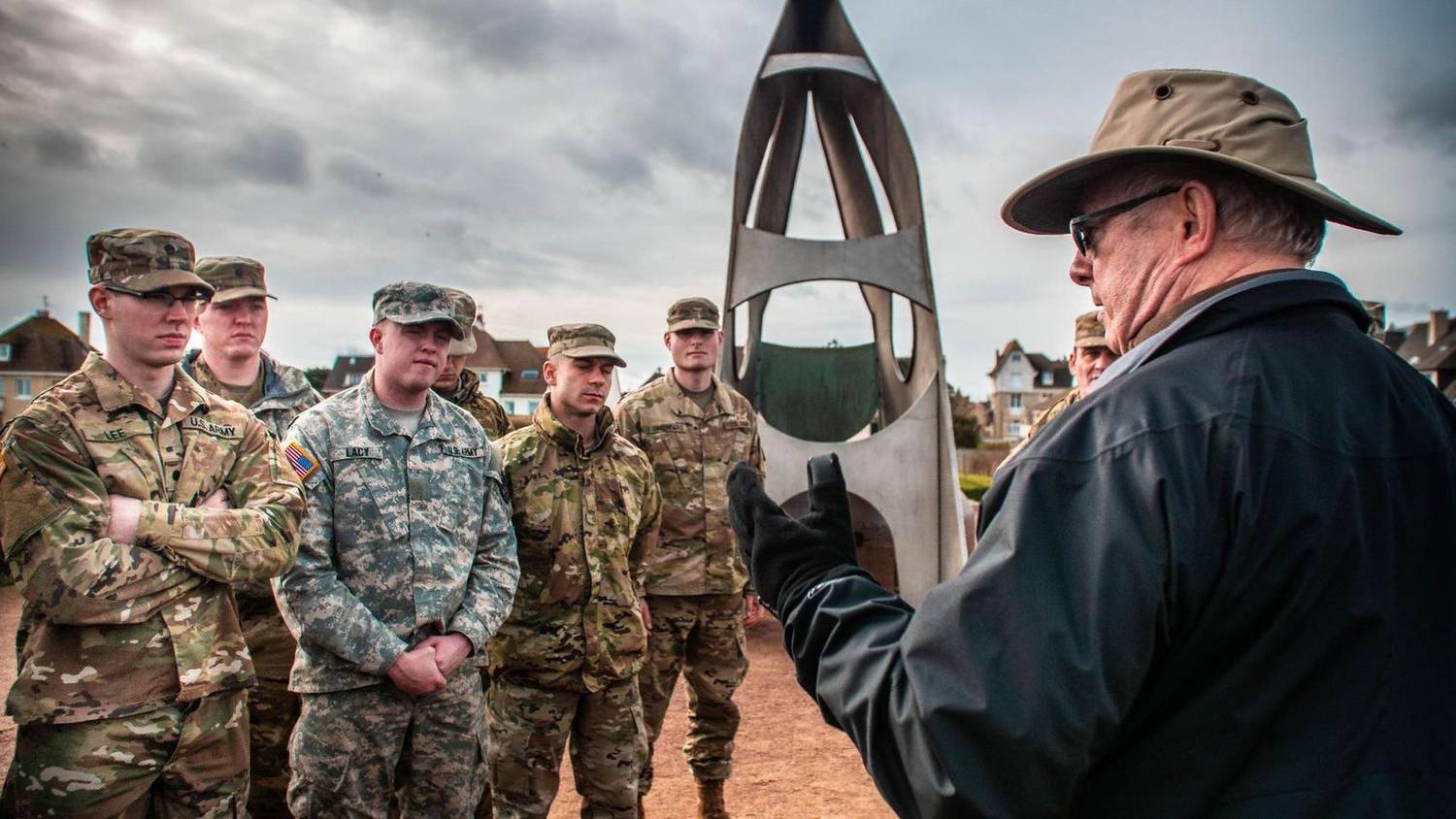 Soldiers being briefed in front of a memorial monument