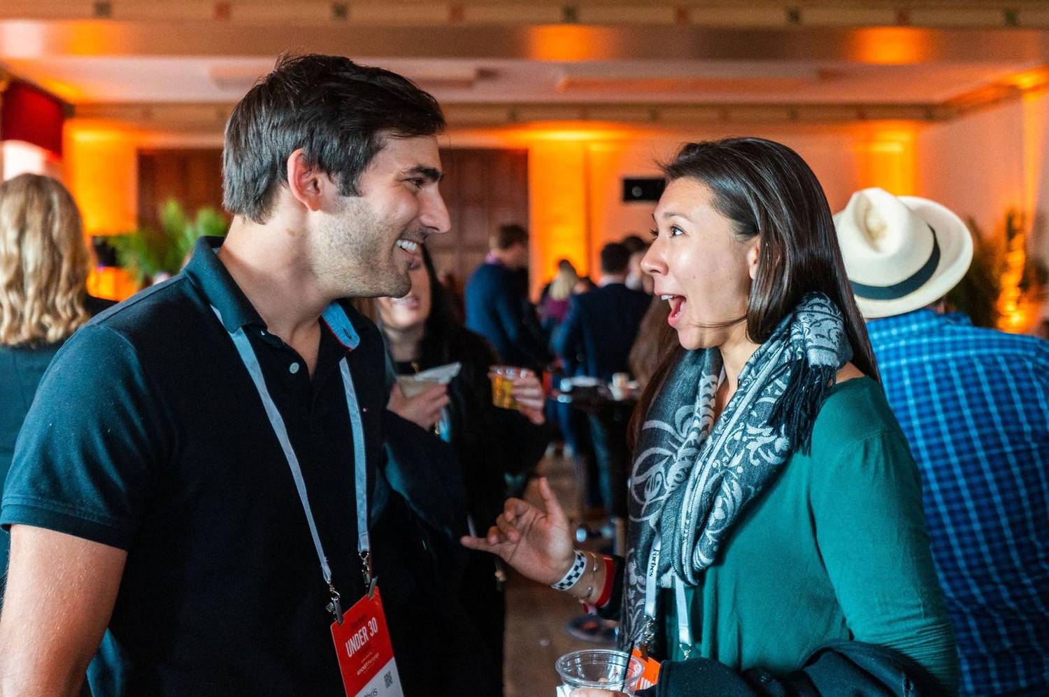 Two attendees laughing mid-conversation at an evening reception