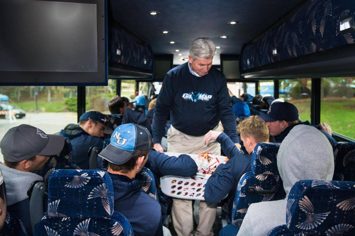 Coach handing out snacks to players seated on a team bus