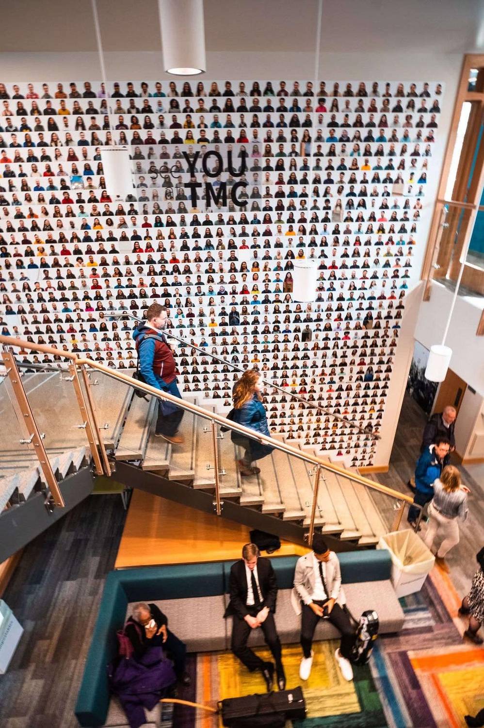 Attendees descending a staircase in front of a wall covered in portrait photos