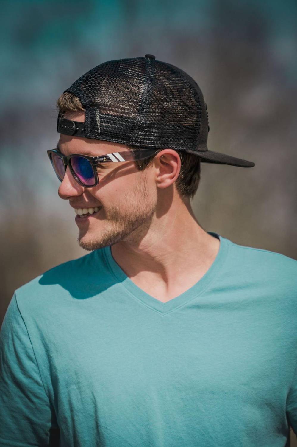 Man in cap and sunglasses smiling in profile