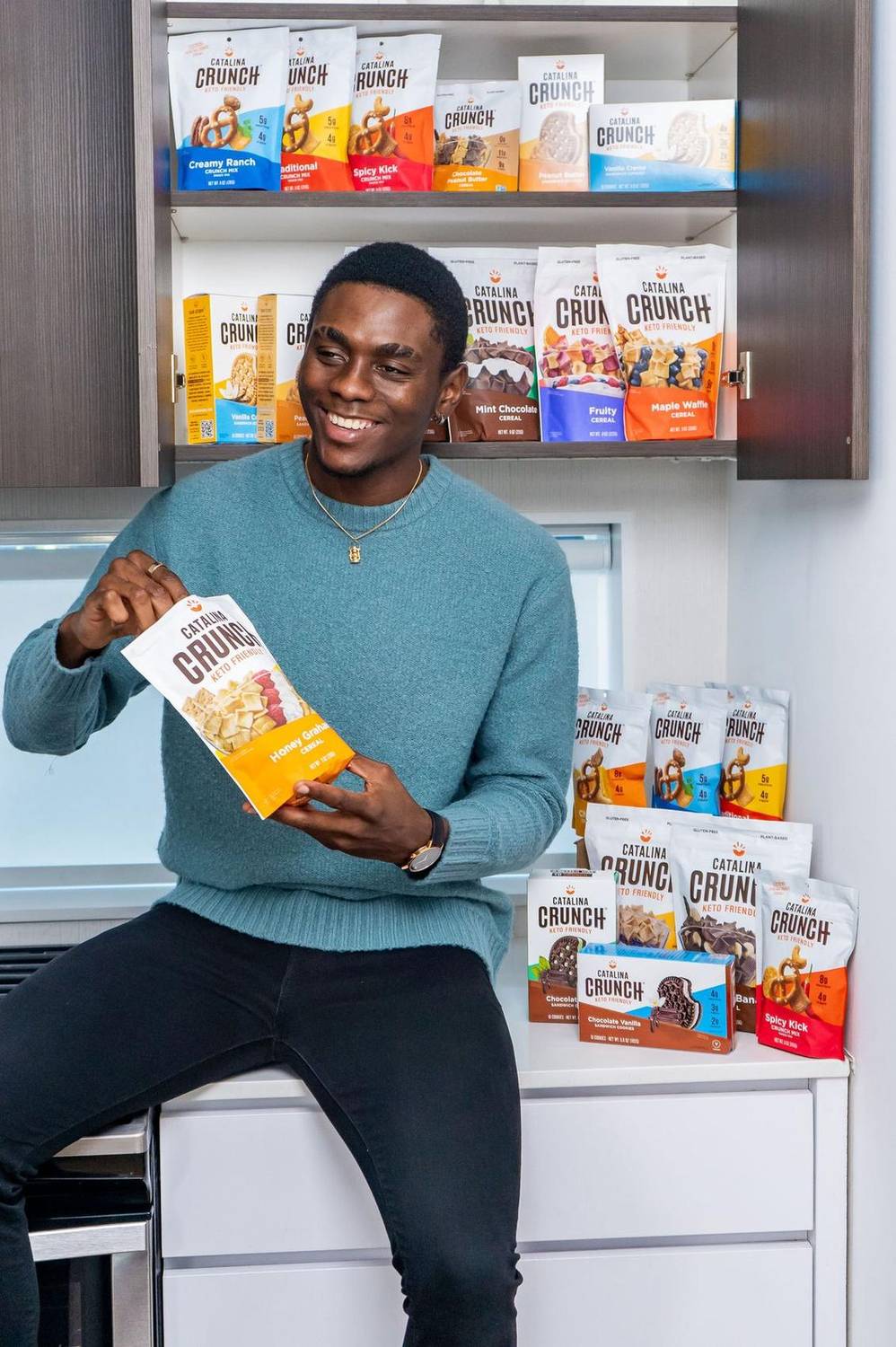 Man smiling while holding Catalina Crunch cereal in front of a stocked shelf