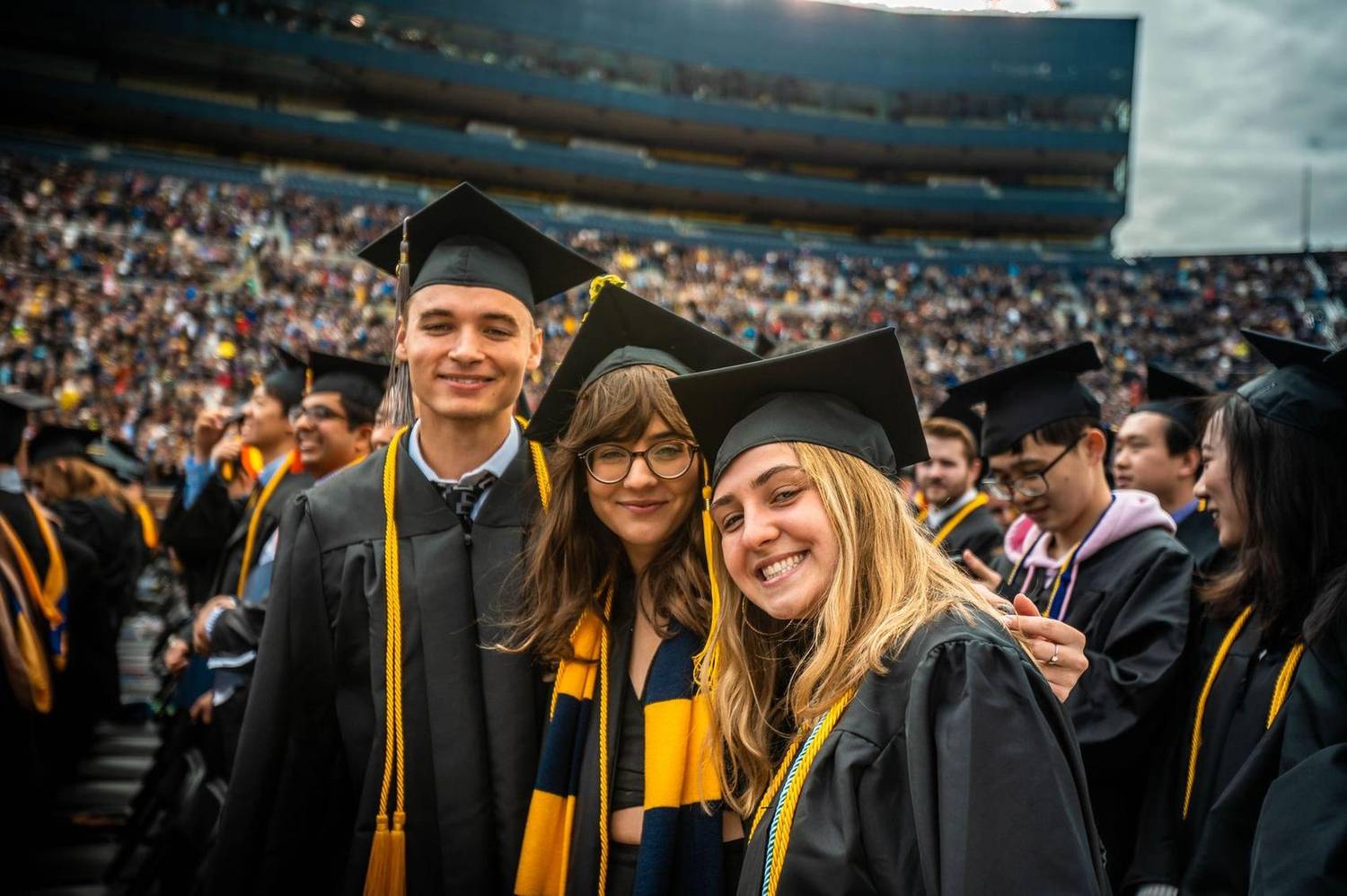 Three graduates smiling together at commencement