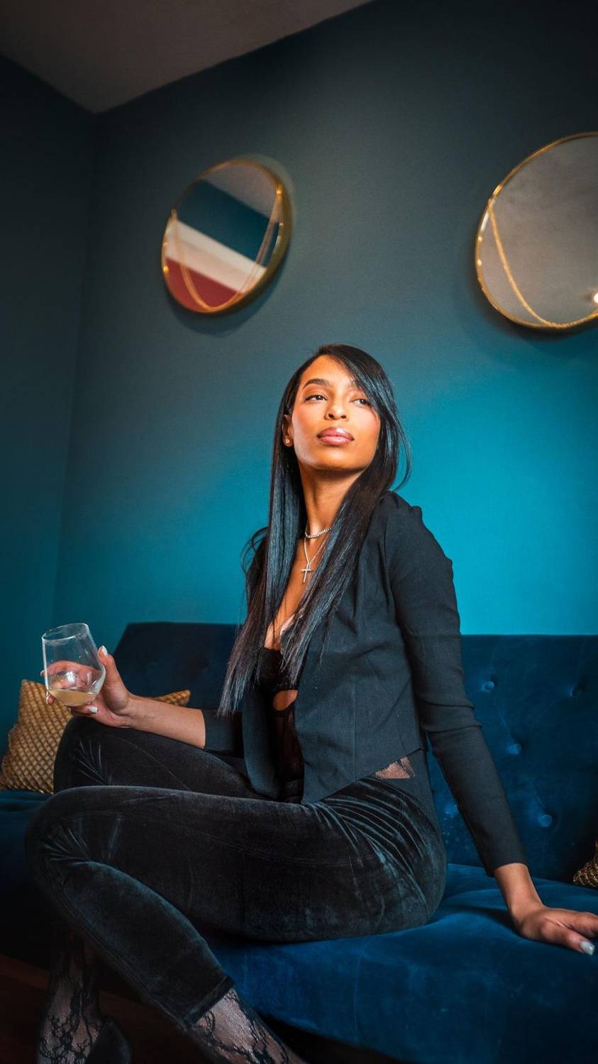 Woman sitting against a teal wall in a sunlit loft