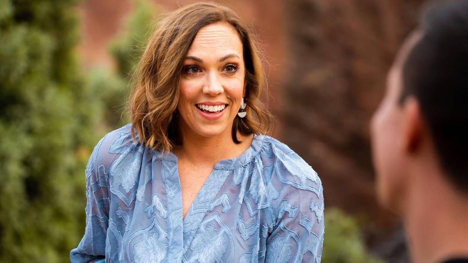 Woman laughing mid-conversation outdoors against red rock cliffs