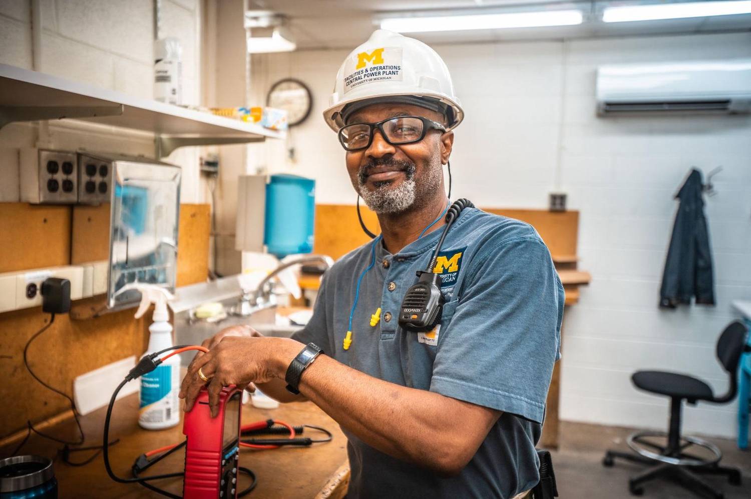 Facilities worker in a hard hat smiling in a power plant workshop