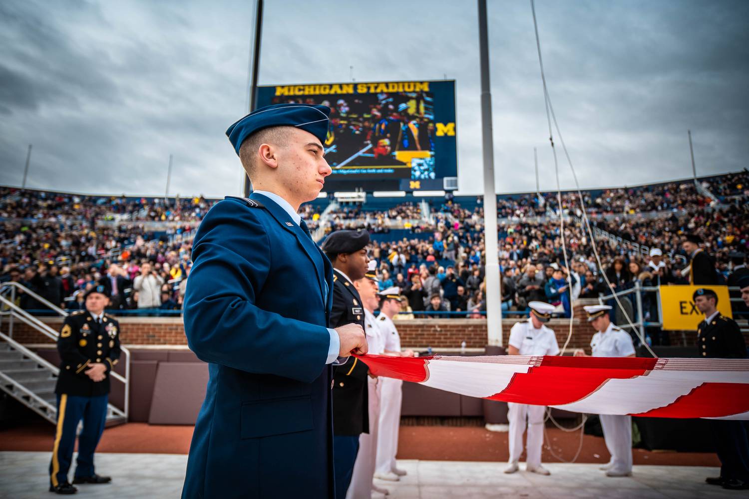 Air Force cadet holding an American flag before a stadium ceremony