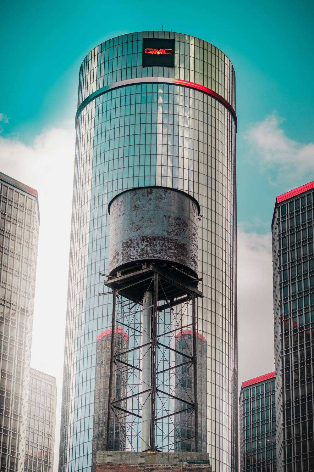 Glass skyscraper with a water tower against a teal sky